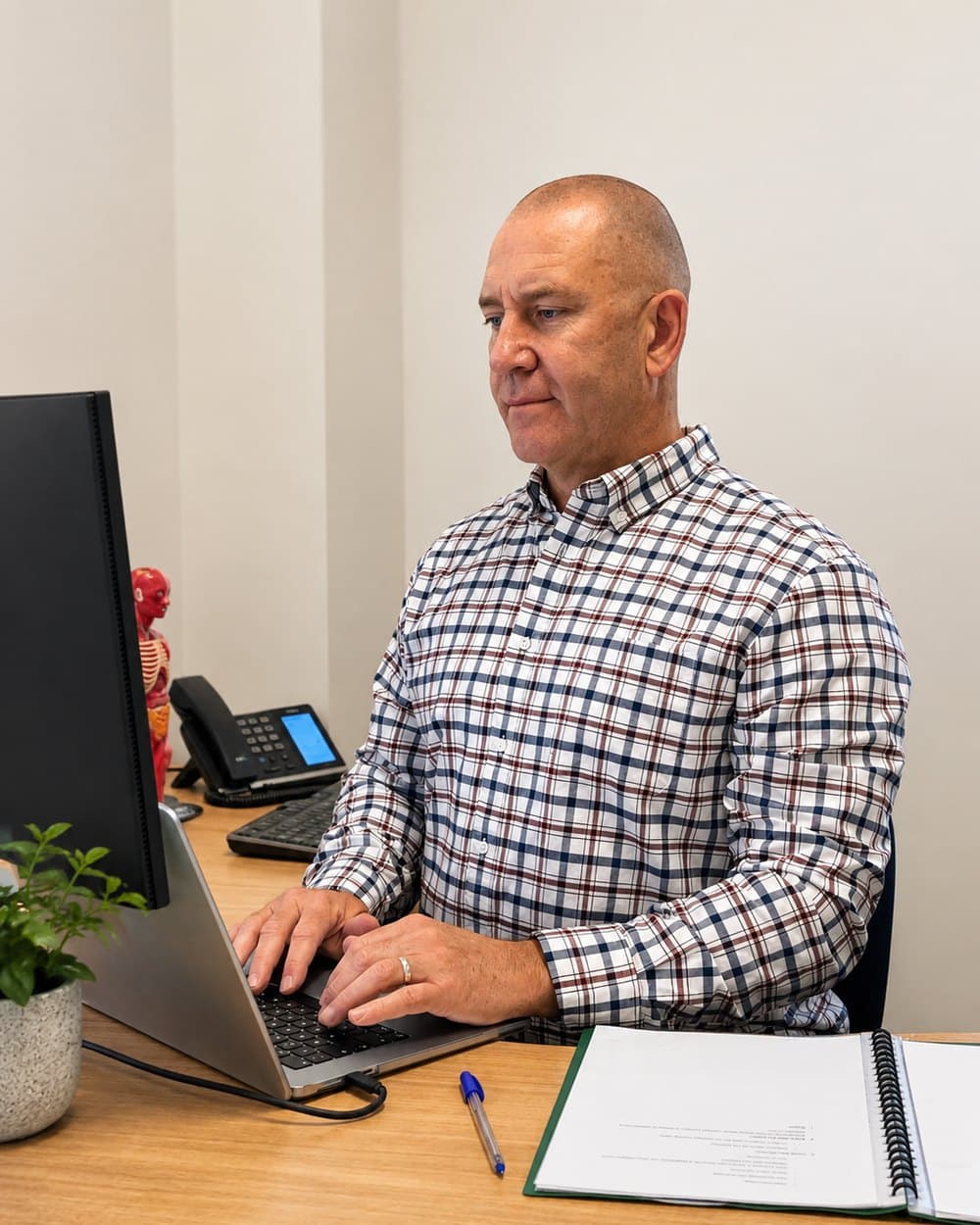 Adrian Hallam reviewing clinical notes at his desk
